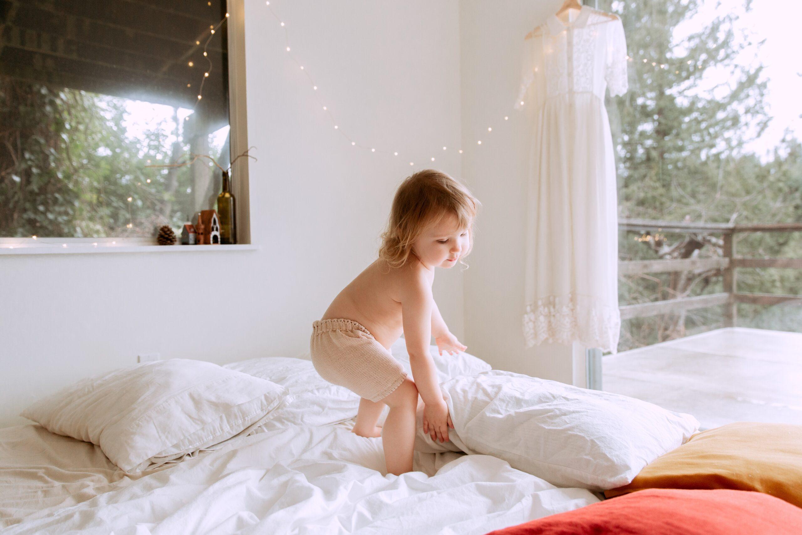 baby on bed holding a pillow