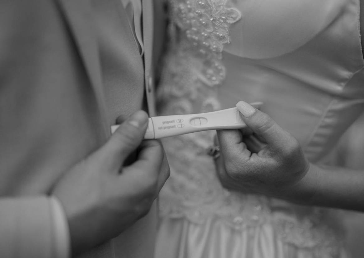 black and white photo of couple holding a pregnancy test